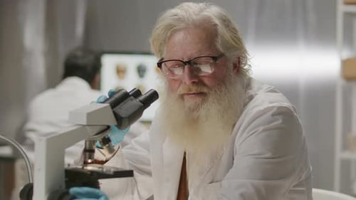 Senior Scientist Using Microscope in Bright Laboratory
