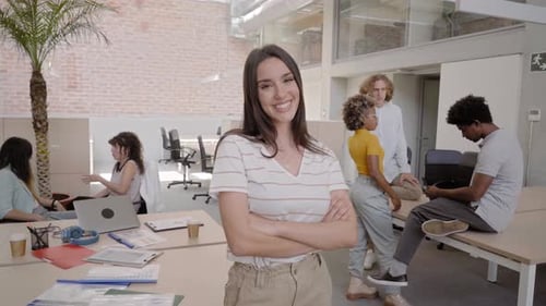 Portrait of a Pretty Young Business Woman Looking at the Camera in a Crowded Office