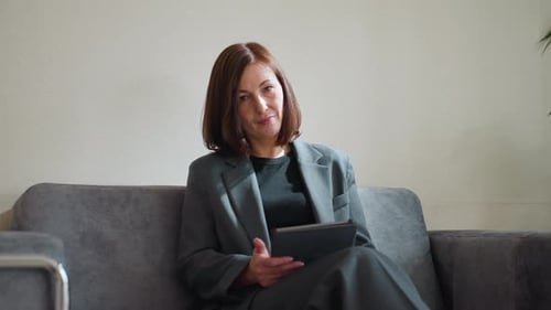 Businesswoman Using Digital Tablet While Seated in Minimalist Office Lounge