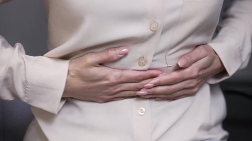 Close up. Female hands holding massaging stomach. Businesswoman feels stomach pain while sitting
