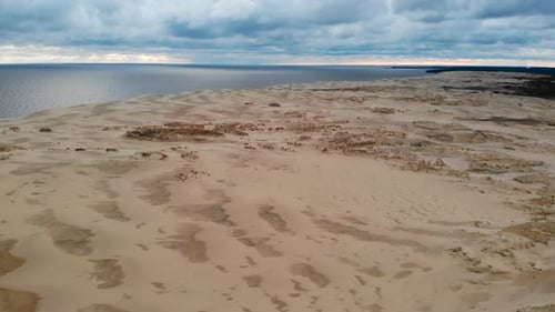 Luftaufnahme von Sanddünen und Meer unter bewölktem Himmel Media