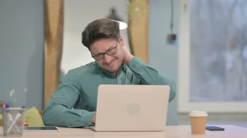 Man Experiencing Neck Pain While Using Laptop
