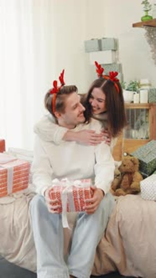 Loving Couple Embracing with Christmas Gifts Indoors