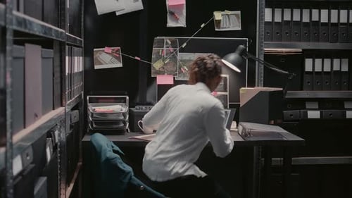 Person Working on Laptop in Dark Archive Room