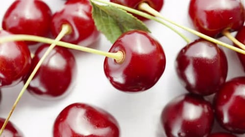 Cherry berries on a white background, One rotates in the middle. Macro