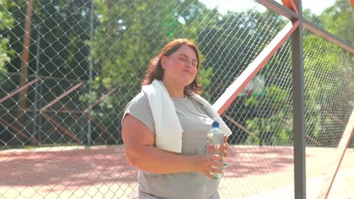 Woman Holding Water Bottle on Outdoor Court