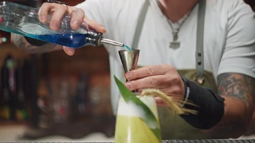 Vídeo de primer plano a cámara lenta vertiendo alcohol en una jarra desde una botella