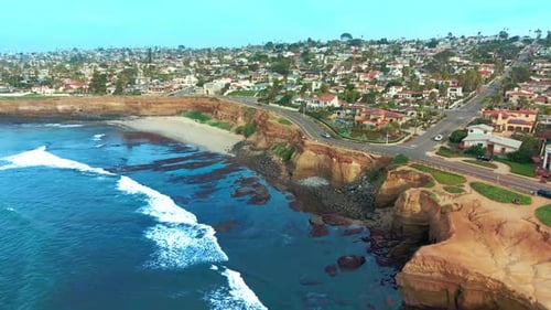 Drone shot of Del Mar city with coastal cliffs, sandy beach and Pacific Ocean waves along shoreline