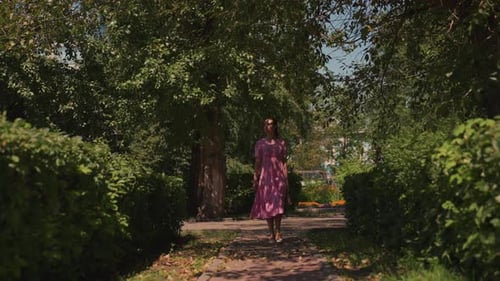 Woman Dressed in Pink Moving Through Calm Shaded Garden Space Elegant Lady in Pink Dress Casually