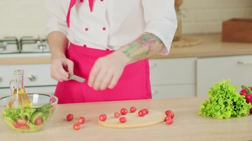 Chef cutting cherry tomatoes in a kitchen