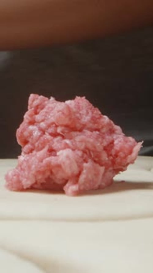 J'étale les morceaux de viande hachée sur la pâte pour les boulettes. Dolly Slider. Vidéo verticale.