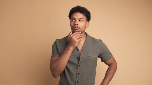 Thoughtful Young Man with Great Idea in Beige Studio