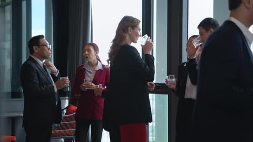 Business professionals networking and enjoying drinks at a corporate event in a modern office