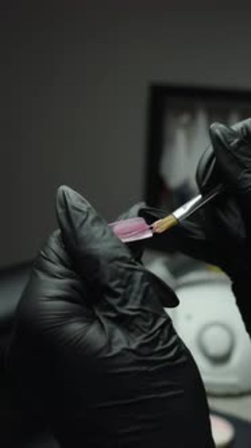 Hands applying clear coat with detail brush