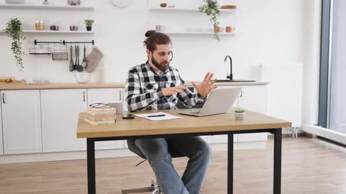 Man Talking on Laptop Computer in Bright Kitchen