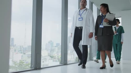 Multiracial Medical Staff Walking along Panoramic Windows inside Clinic