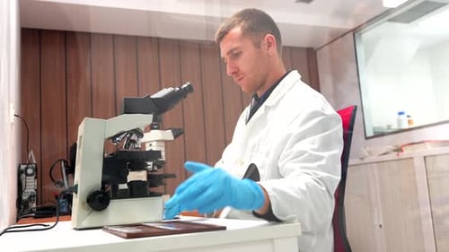 Young Adult Examining Specimen Under Microscope in Lab