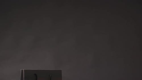 Sac cadeau noir avec poignées noires sur fond gris foncé avec espace de copie