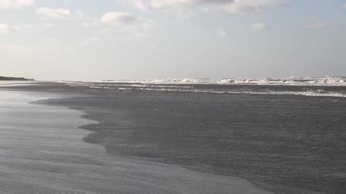 No people at Stormy day at sandy beach with crashing waves during sunny day. Wide shot.