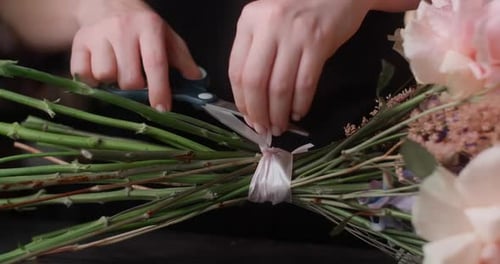 Le fleuriste attache un ruban autour des fleurs