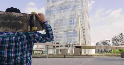 Portrait a boy practices skateboarding in the middle of the city, between buildings and skyscraper