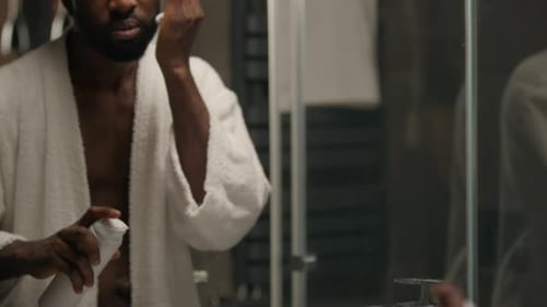 Young Adult Man Shaving in Bathroom Mirror