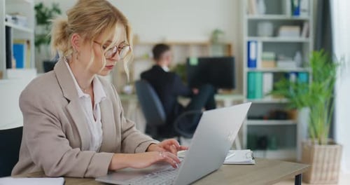 Woman Writing on Laptop in Office