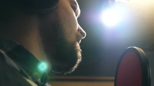 Profile of Male Singer in Headphones Singing Song Into the Microphone at Sound Studio Young Man