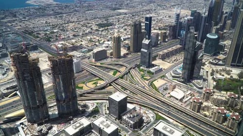 View from the top of the Burj Khalifa of buildings being built and busy roads. City life in Dubai.