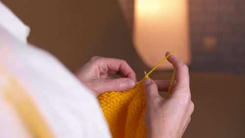 Woman Knitting Bright Yellow Yarn at Home