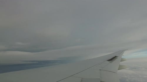 Airplane wing soars through cloudy skies on a journey above the world