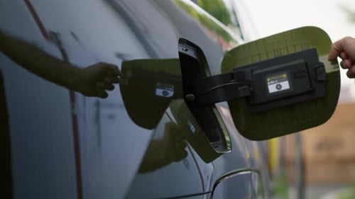 Close Up of Driver Opening Electric Vehicle Charging Port Flap to Charge Battery