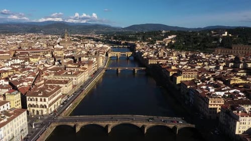 Drone flying fast above Arno River and city on a sunny day in Florence in Italy in 4k.