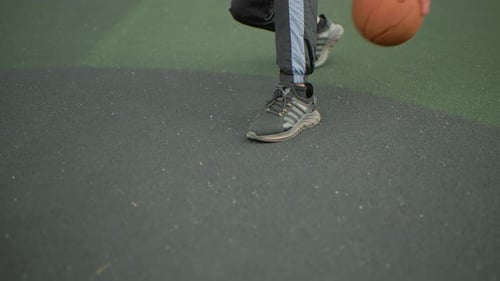 Man Dribbling Basketball on Outdoor Court During the Day
