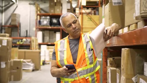 Warehouse supervisor with smartphone and notepad portrait stands proudly