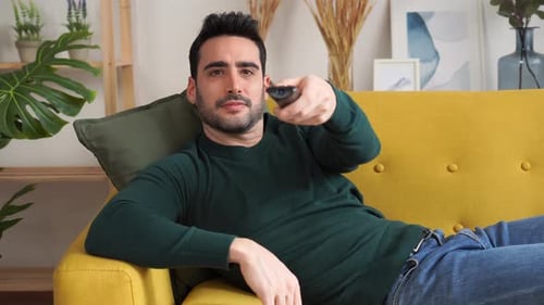 Man Relaxes on Couch with Remote Control