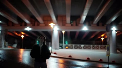 Young Woman Standing Alone Under the City Overpass at Night Illuminated By Soft Ambient Lighting