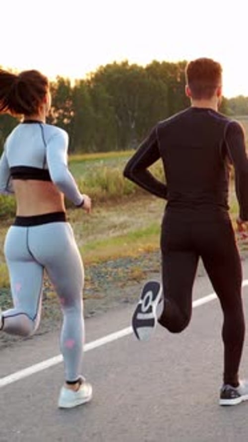 Athletic Couple Running on Road at Sunrise
