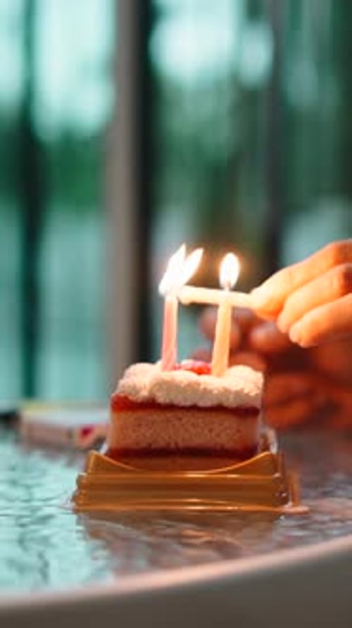 Hand Lighting Candles on a Small Birthday Cake