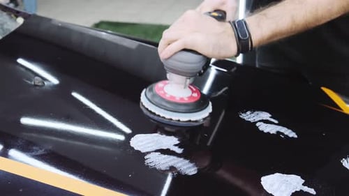 Fahrzeug-Detaillierung Man trägt eine spezielle Polierpaste (Creme) auf die Motorhaube eines Autos auf und schmiert sie mit