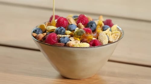 Honey Poured on Nutritious Cereal Breakfast with Berries