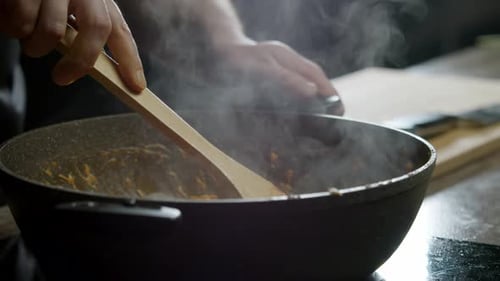 Person stirs food in a steaming pot