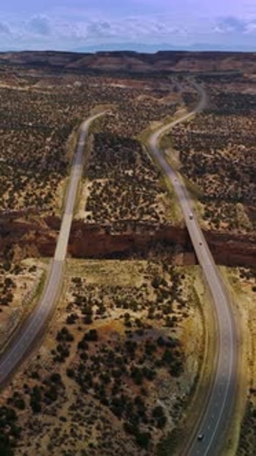 Two long highways passing through the deserted land with little green bushes.