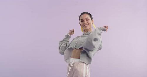 A playful young woman posing against a purple background