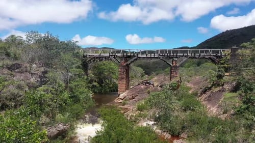 Eine alte verlassene Brücke überquert den Fluss in den kargen Hügeln. 4K-Videos. nähernde Aufnahme.