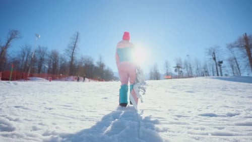 Snowboarder Walking Up Snowy Mountain on Sunny Day