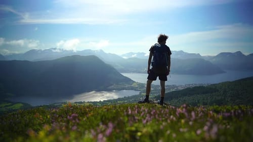 Hiker walks up and poses in front of a beautiful view.