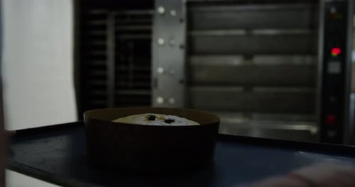 Baker Placing a Cake in an Industrial Oven
