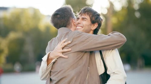 Happy Gay Couple Embracing and Kissing in a Park