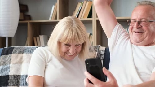 Happy Senior Couple Share Joyful Moment With Smartphone